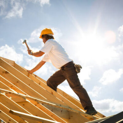 carpenter on roof trusses backlit with sunflare