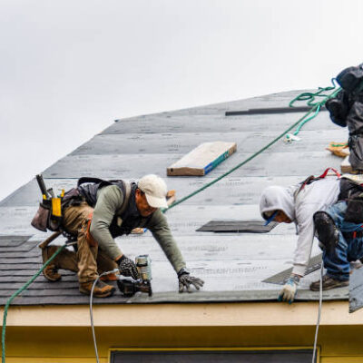 Everett WA. USA - 03-23-2021: Crew Installing New Shingles on Roof on a Rainy Day